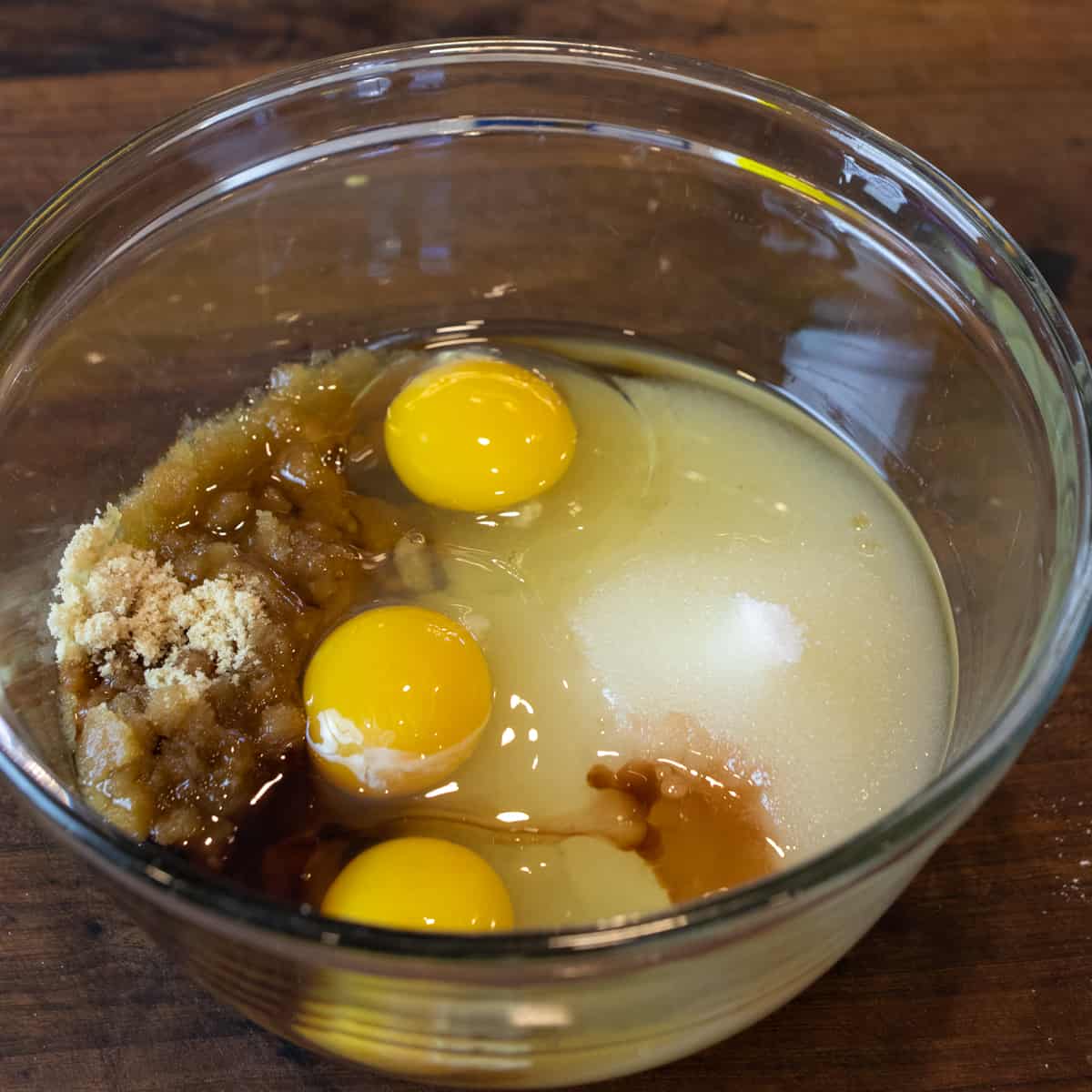 A glass bowl with eggs, sugars and vanilla.