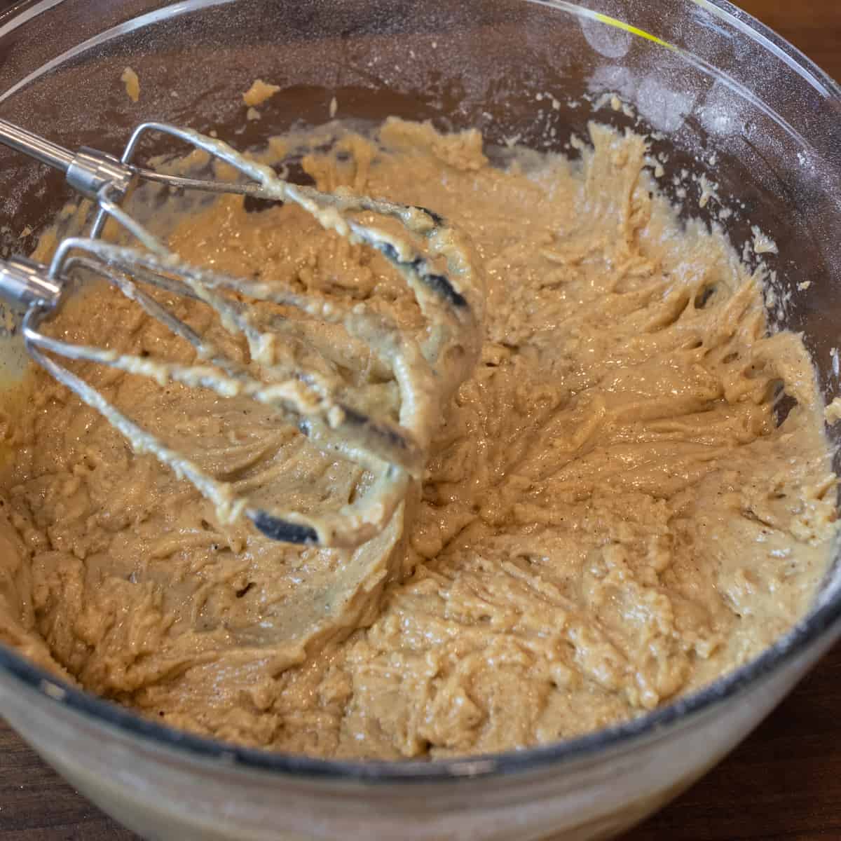 A glass bowl with bread batter with mixer beaters resting above.