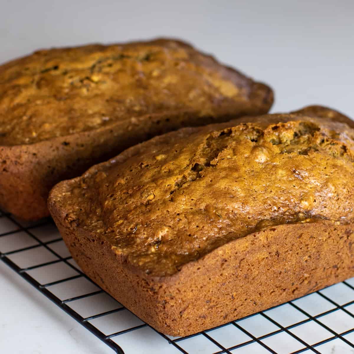 Two loaves of zucchini bread on a cooling rack.