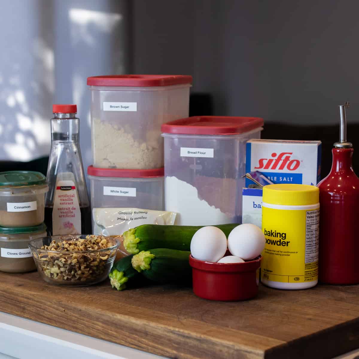 Ingredients needed to make zucchini bread gathered and placed on a cutting board.