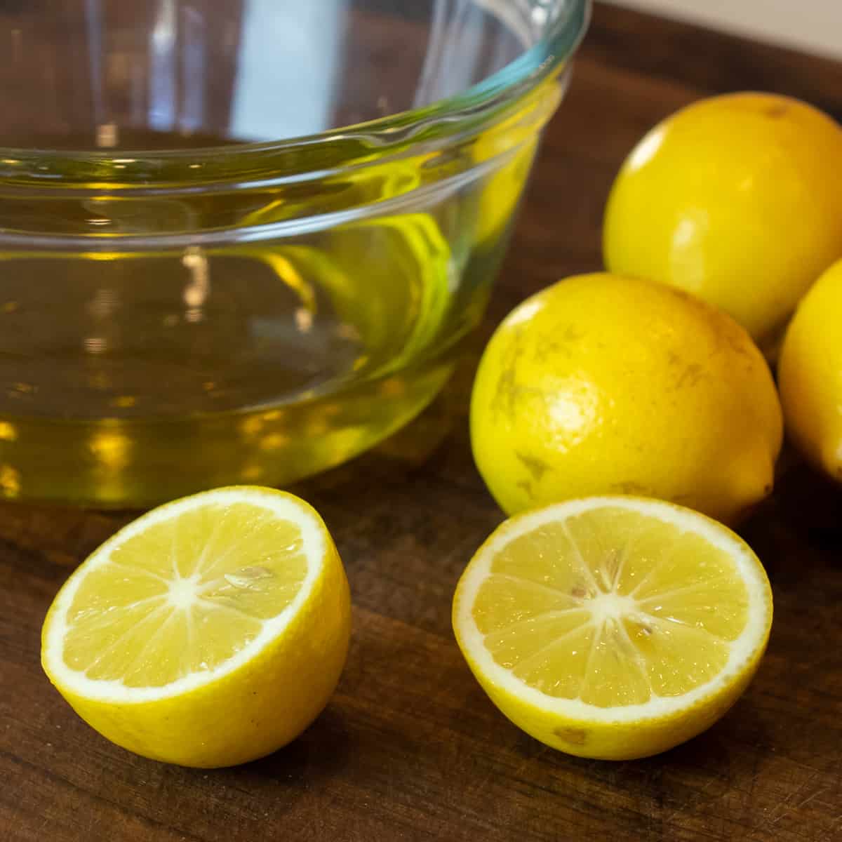 Cut Meyer lemon next to a glass bowl with oil.