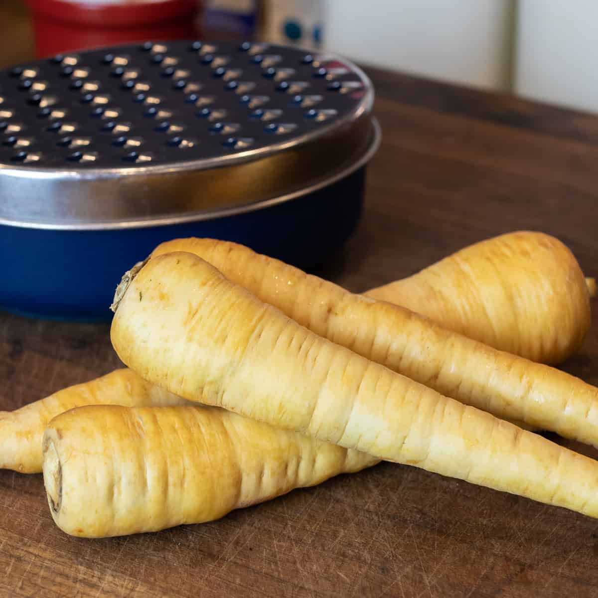 Whole parsnips next to a grater.