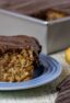 A piece of cake with chocolate icing next to two whole parsnips.