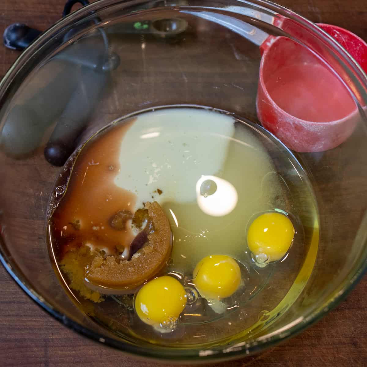 Eggs, oil and sugars in a glass bowl.