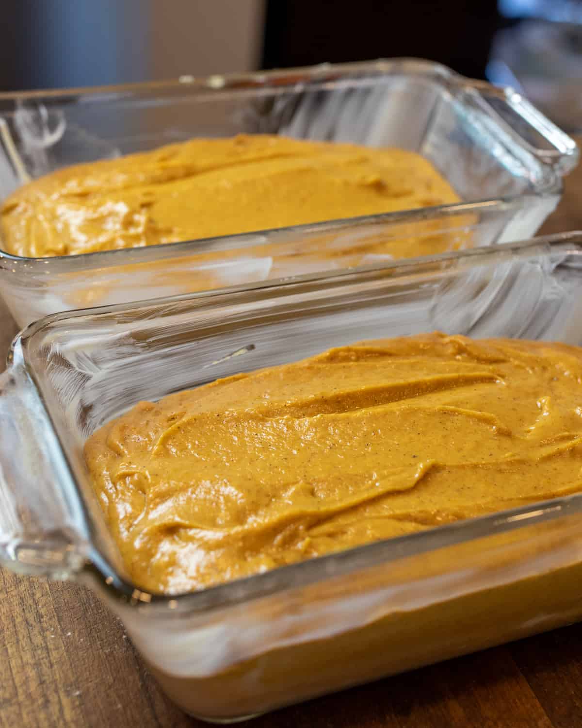 Two glass loaf pans filled with pumpkin batter.