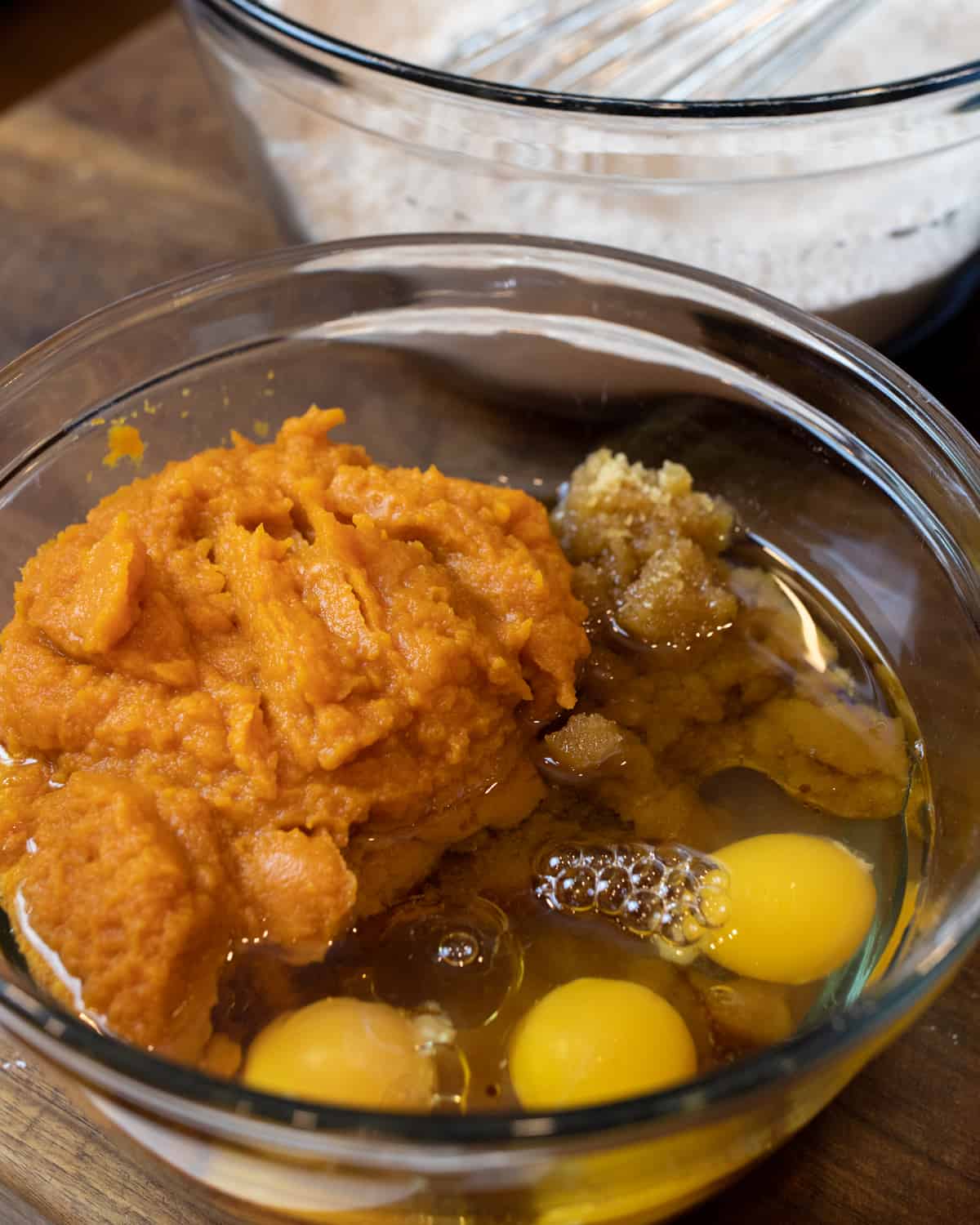 Mashed pumpkin, eggs and sugar in a glass bowl.