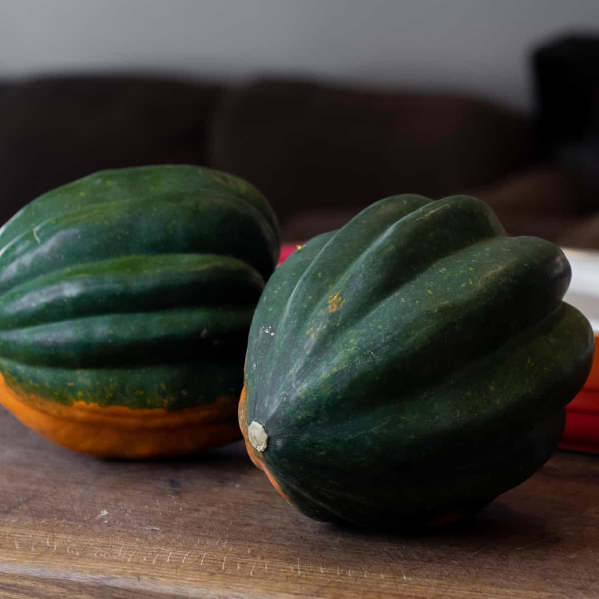 Two whole acorn squash on a cutting board.