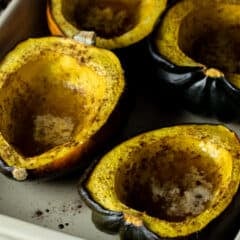 Cooked acorn squash halves in a baking dish.