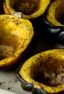 Cooked acorn squash halves in a baking dish.
