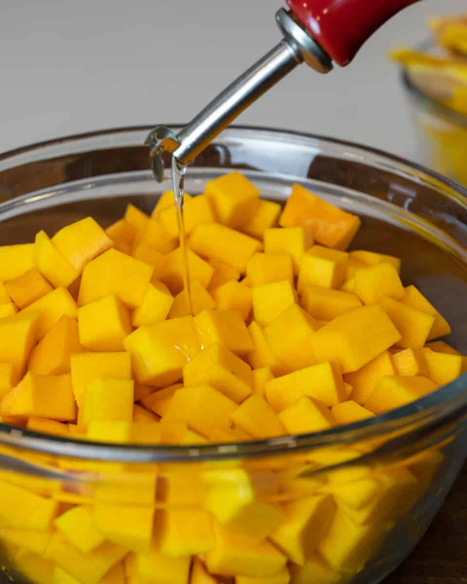 Oil being drizzled on top of cubed squash.