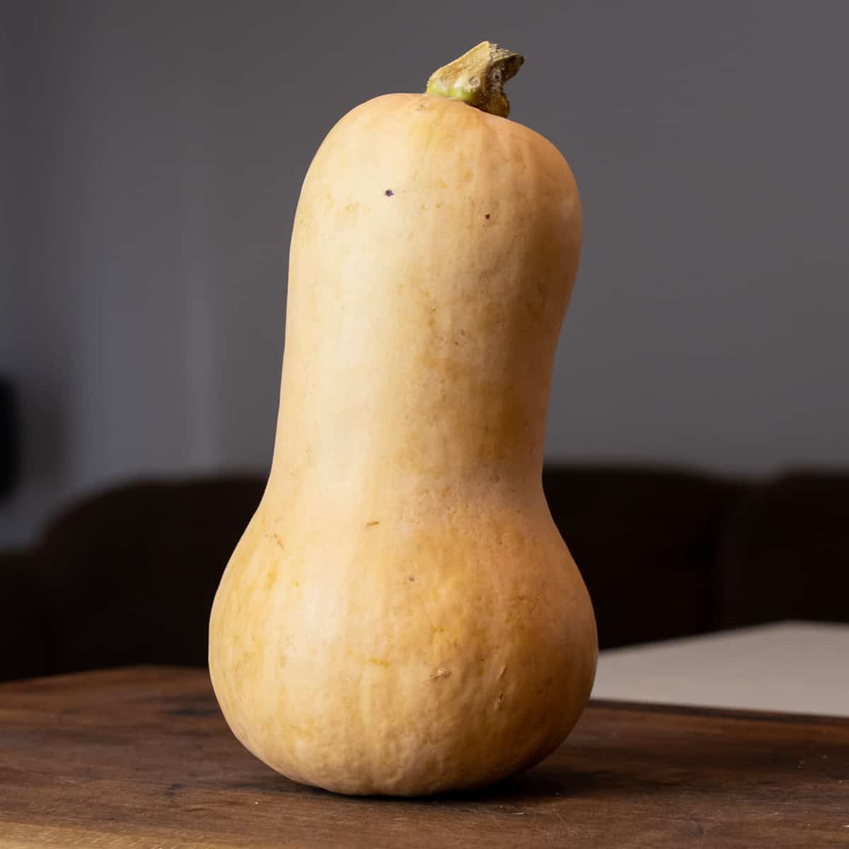 A whole butternut squash on a cutting board.