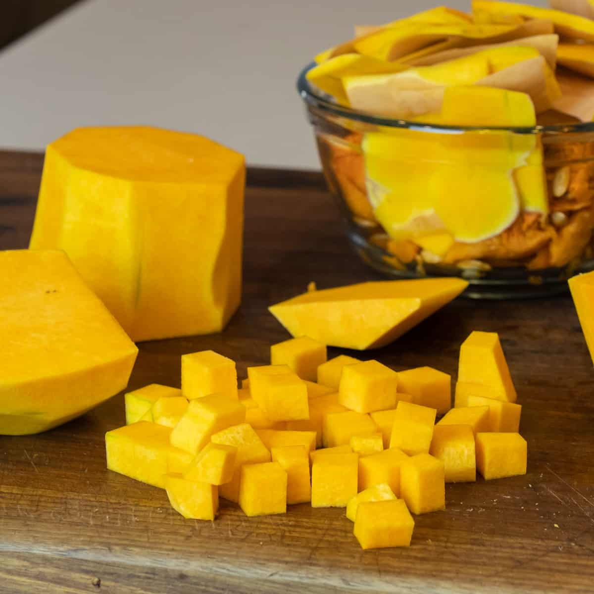 Peeled squash that has been diced into chunks with the peel in a glass bowl.