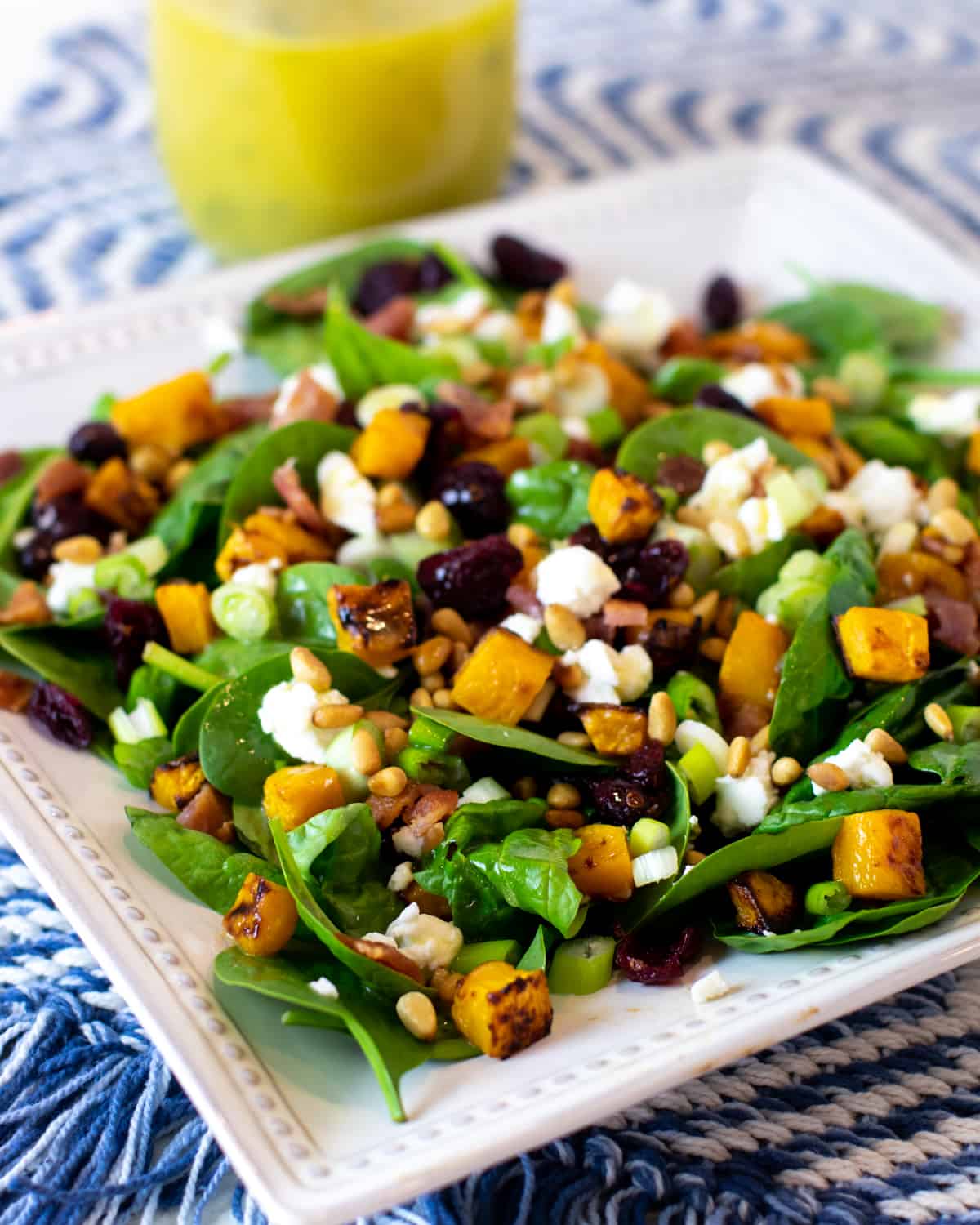 A plate full of salad with a jar of lemon vinaigrette behind.