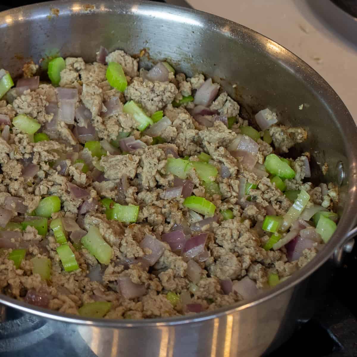 Cooked ground turkey, onions and celery in a frying pan.