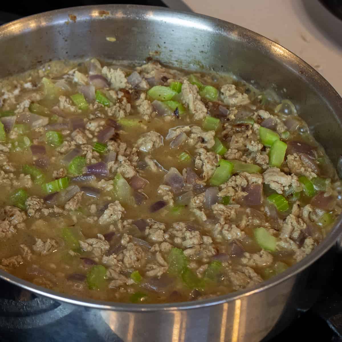A skillet with rice, broth, turkey and other ingredients.