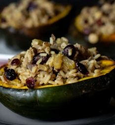 A close up with roasted squash half filled with stuffing.