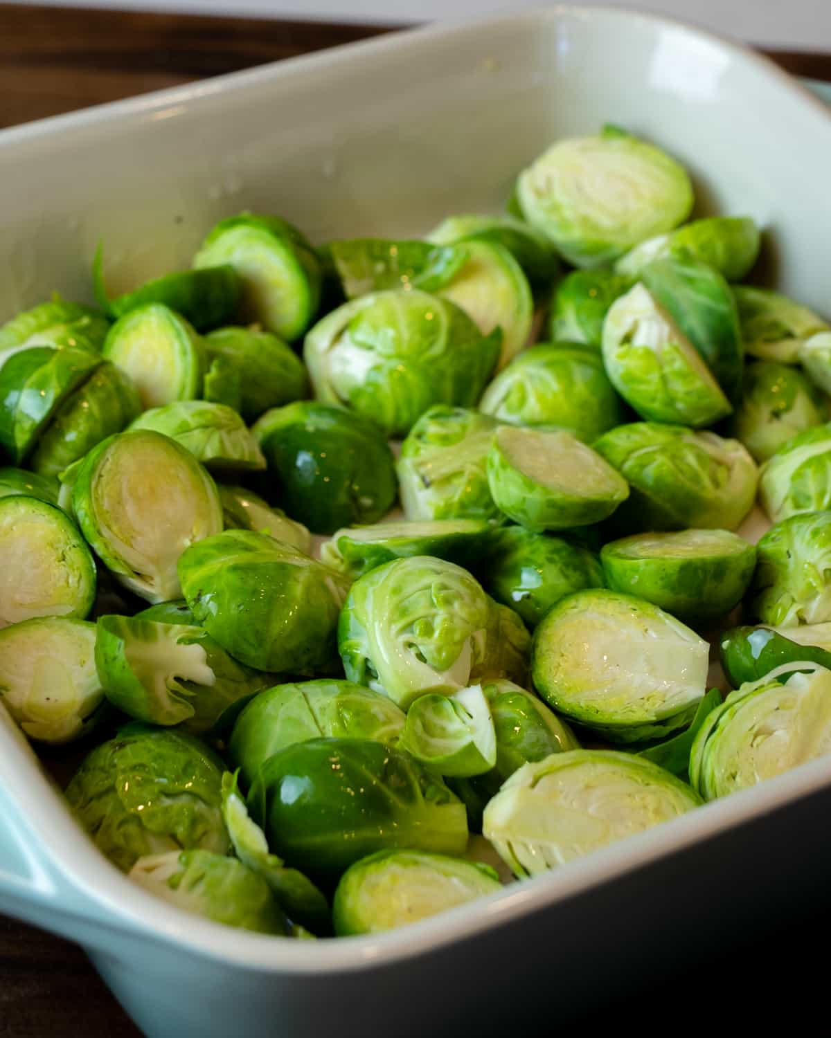 Raw Brussels sprouts cut in half and coated in oil.