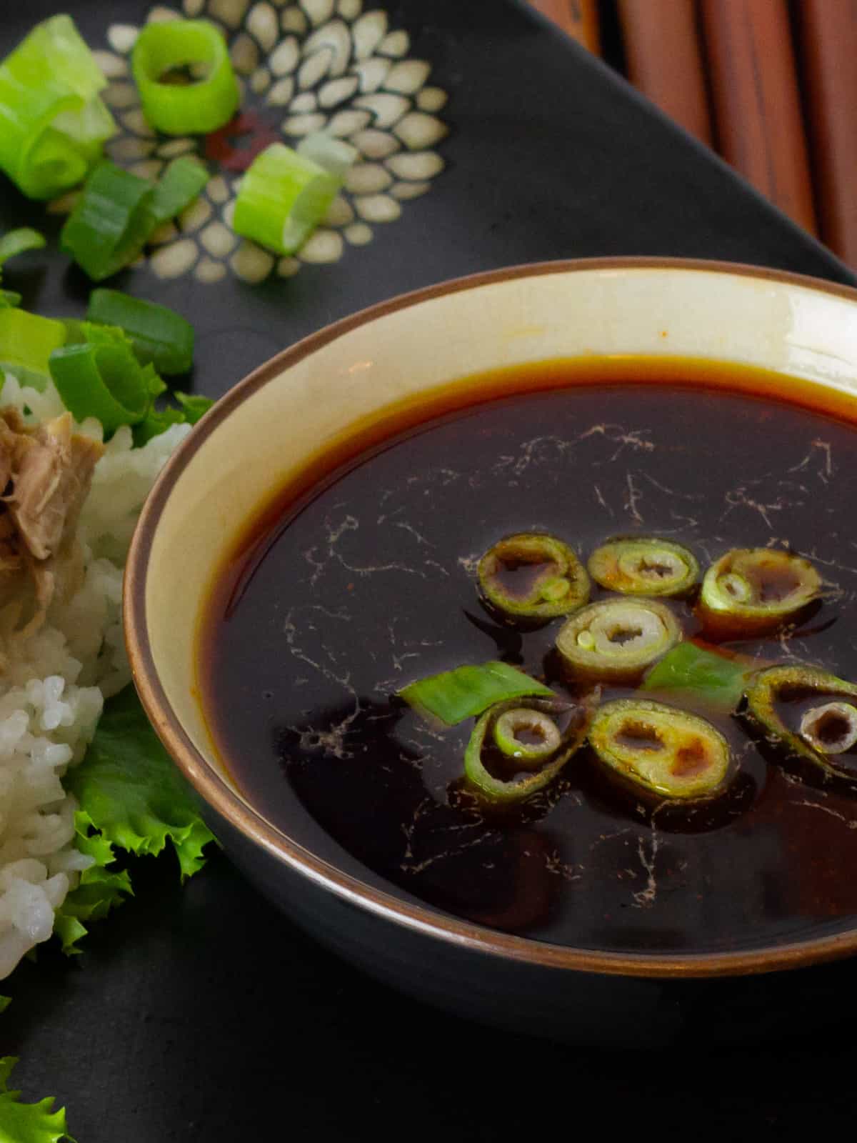 Sauce in a small bowl with sliced green onions.