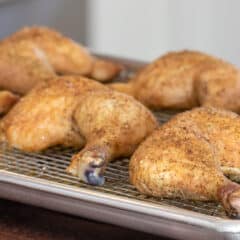 Cooked chicken leg quarters on a baking sheet.