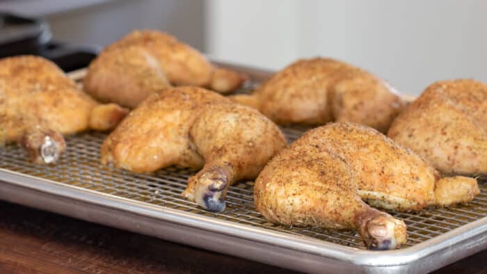 Cooked chicken leg quarters on a baking sheet.