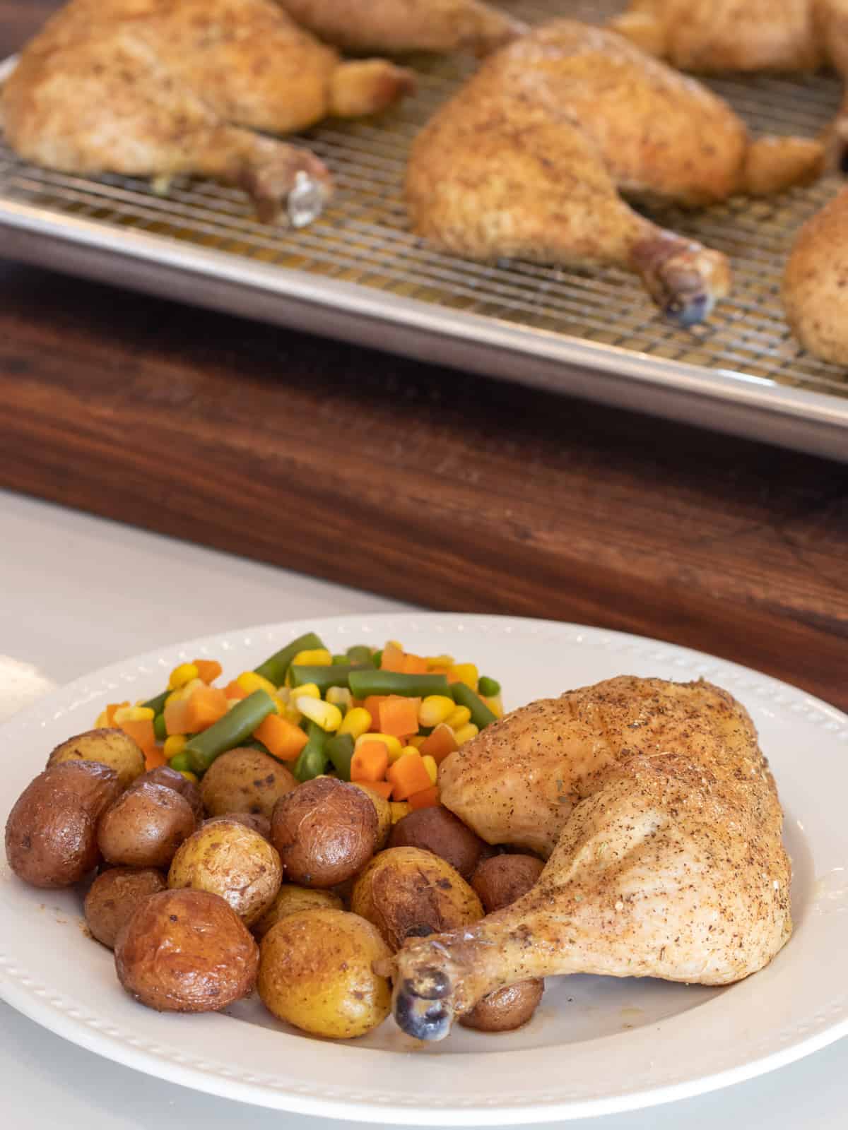 A dinner plate with baked chicken, potatoes and mixed vegetables.