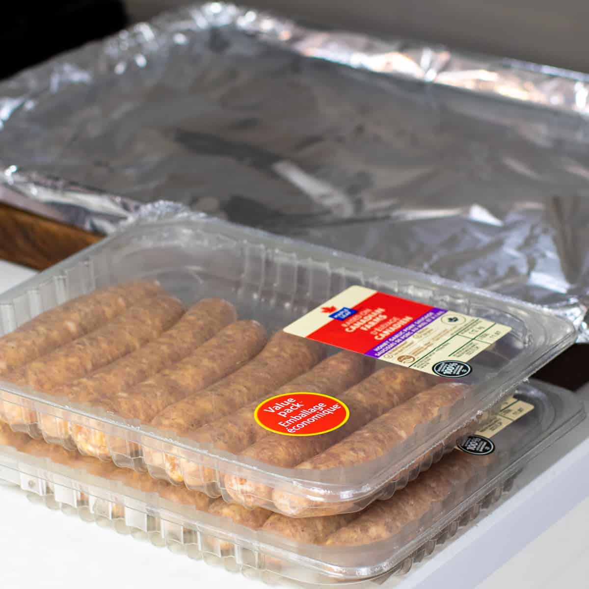 Packages of Italian sausages next to a baking sheet.