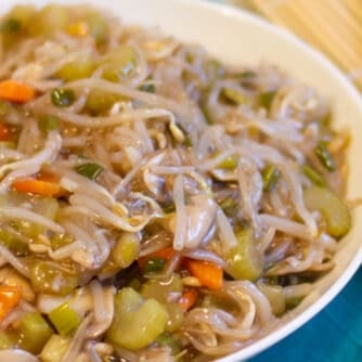 A bowl of stir fried vegetables and a pair of chopsticks.