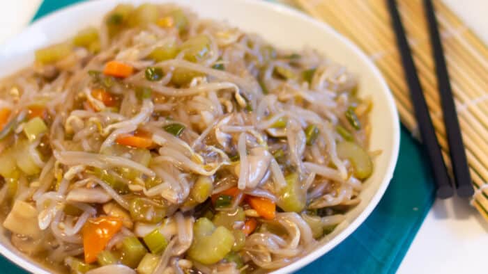 A bowl of stir fried vegetables and a pair of chopsticks.