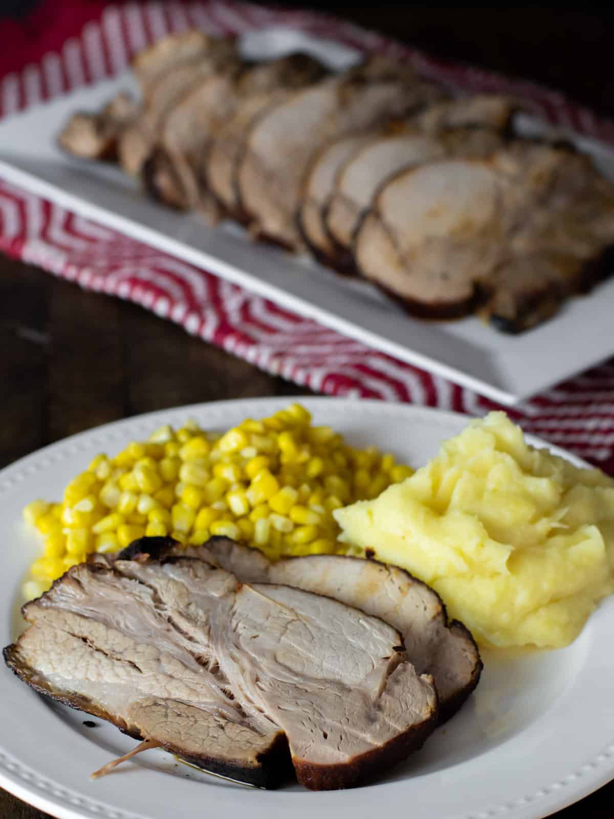 A dinner plate with a slice of pork roast, mashed potatoes and corn.
