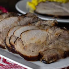 Pork roast sliced and placed on a whit platter.