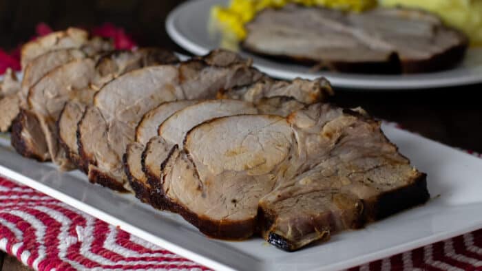 Pork roast sliced and placed on a whit platter.