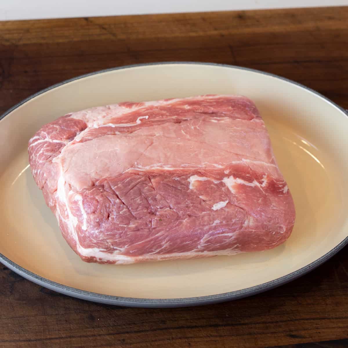 Raw pork roast in a roasting dish.