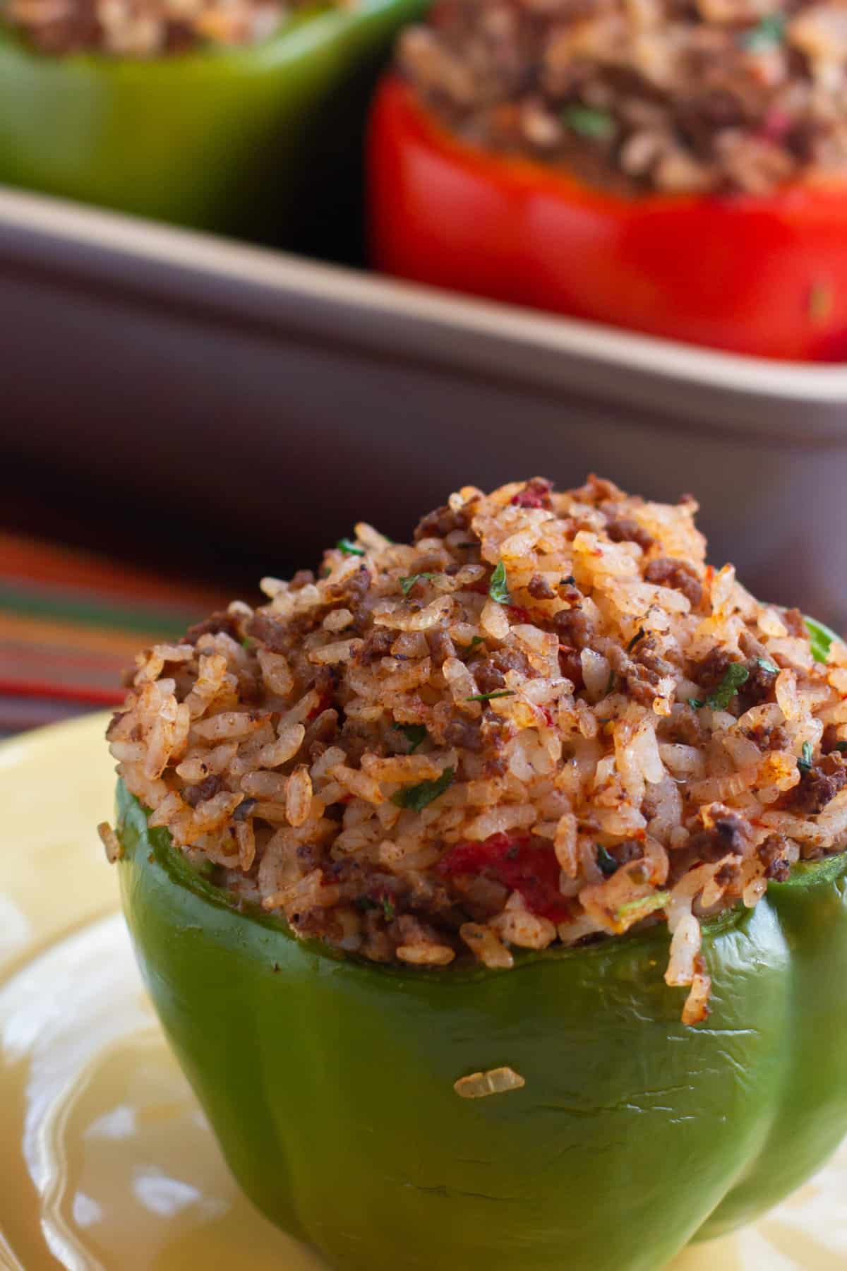 A baked green pepper on a plate filled with rice and ground beef.