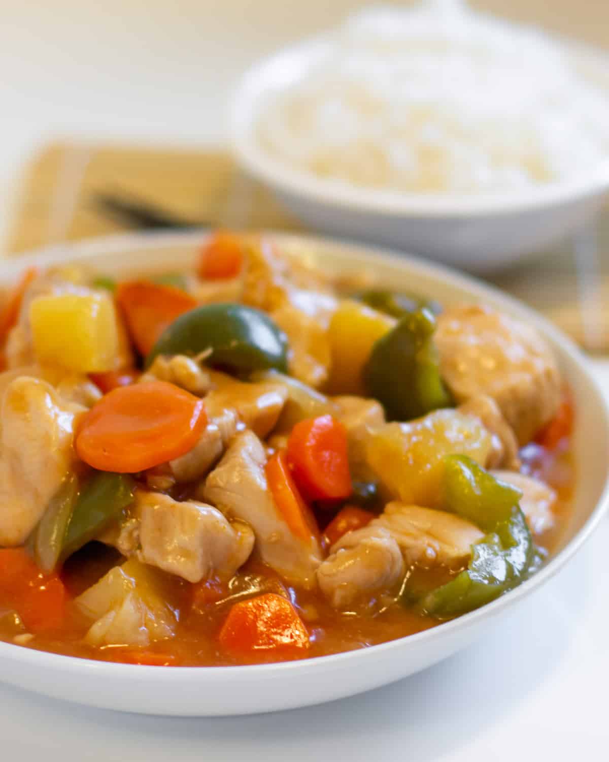 A bowl of chicken stir fry in front of another bowl of rice.