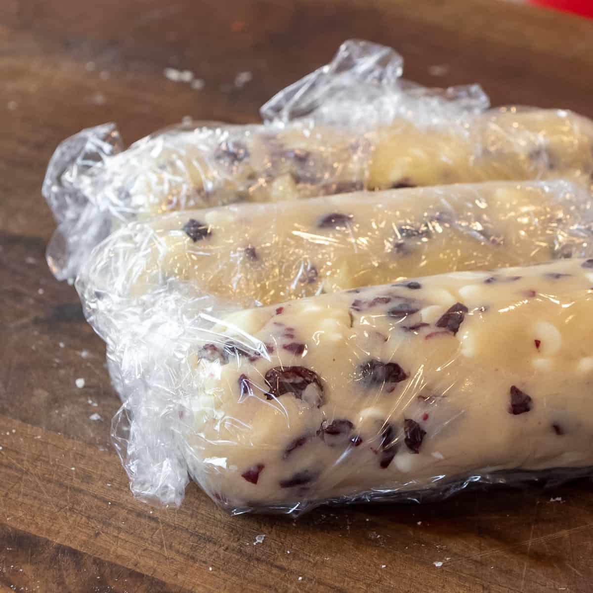 Cookie dough logs covered in plastic wrap.