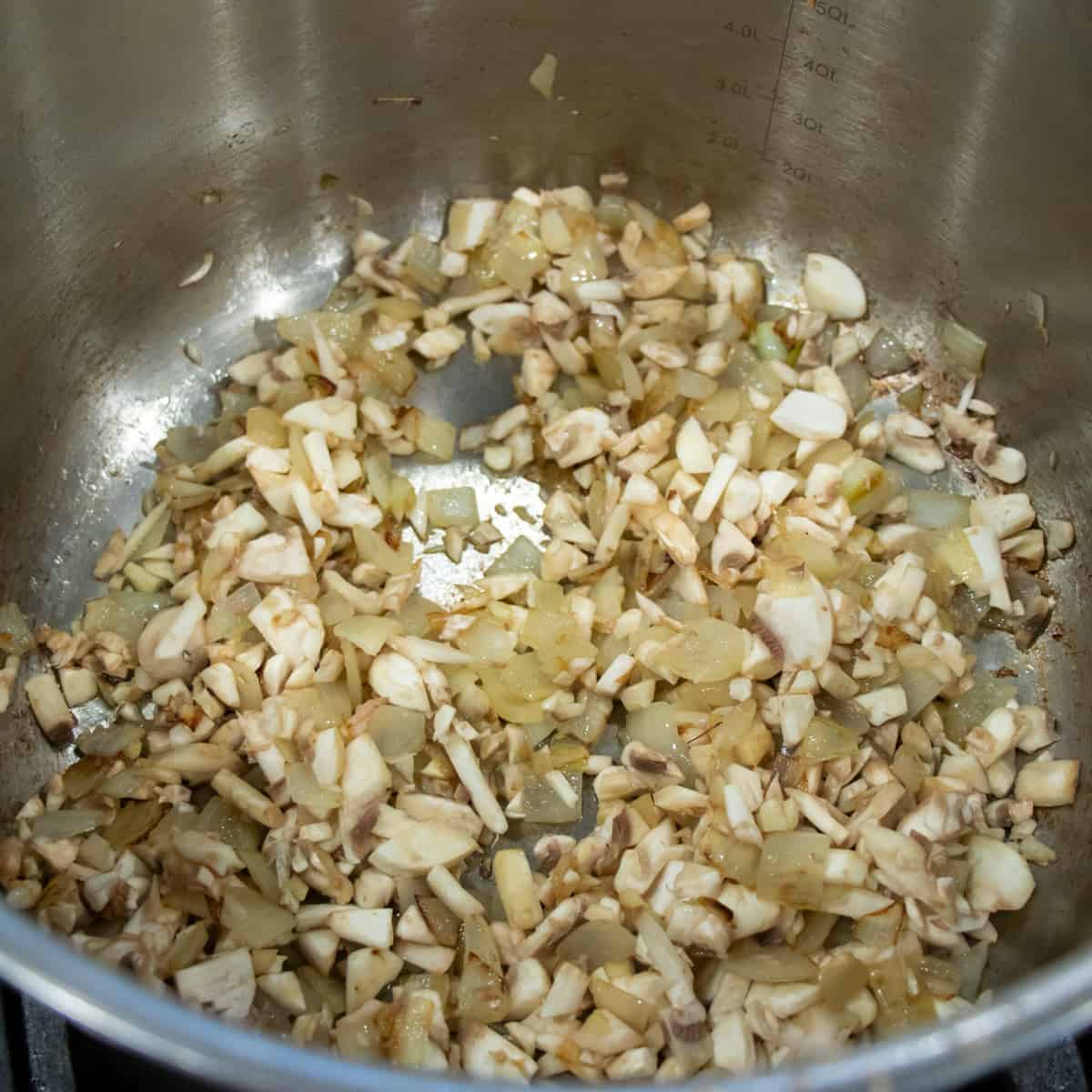 Onions, garlic and mushrooms cooking in a saucepan.