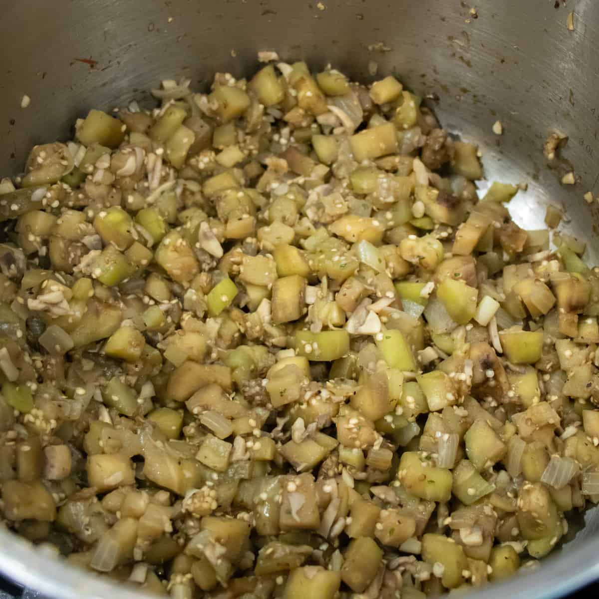 Eggplant and other vegetables being sautéed in a saucepan.