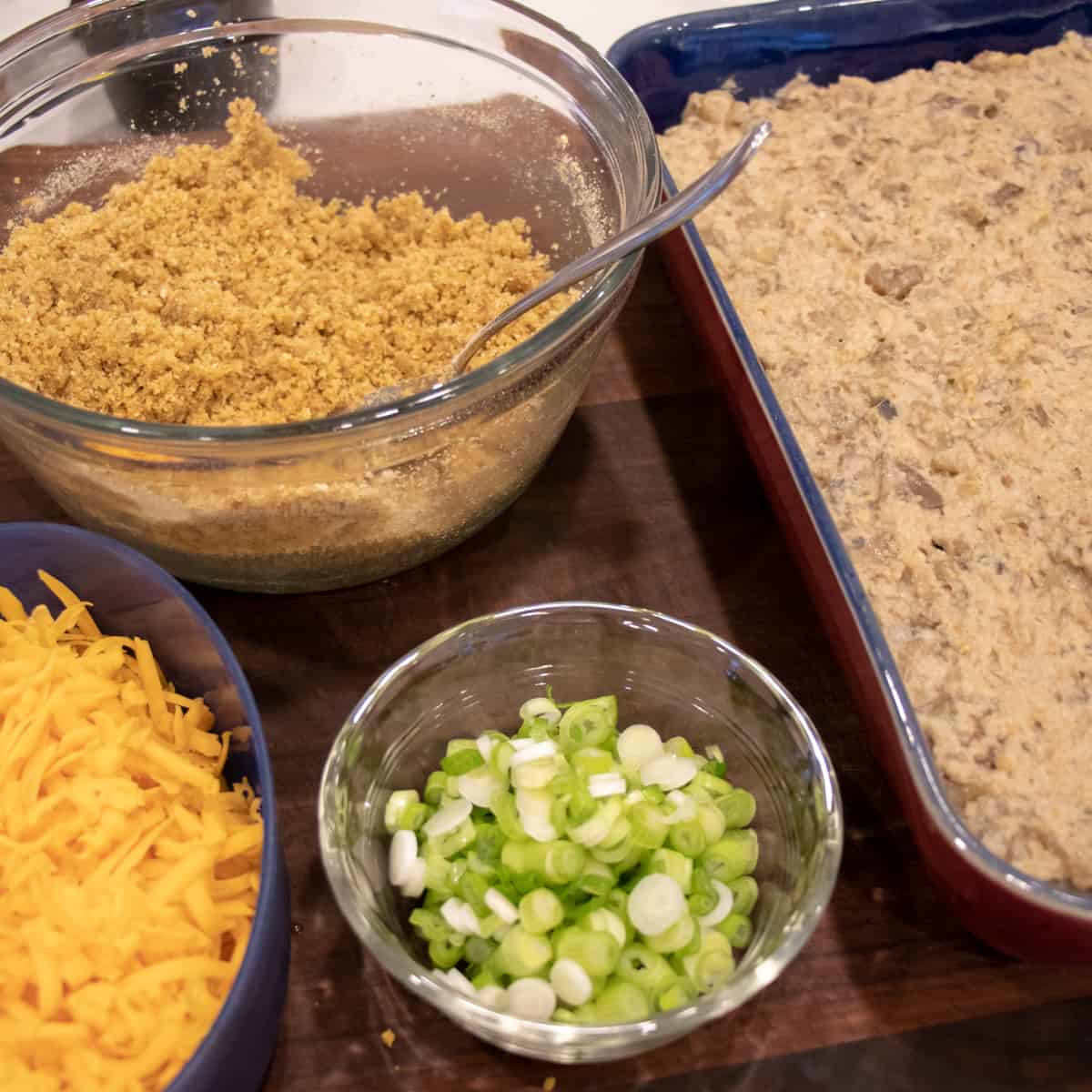 Bowls of grated cheese, sliced onions and bread crumbs.