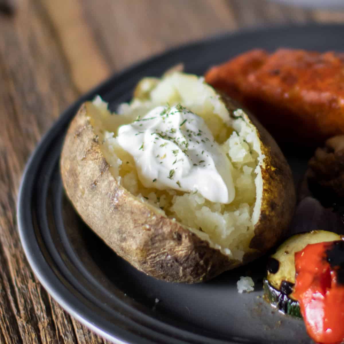 Cooked potato with a spoonful of sour cream on top.