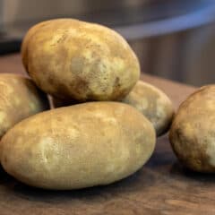 Russet potatoes stacked on a cutting board