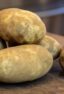 Russet potatoes stacked on a cutting board