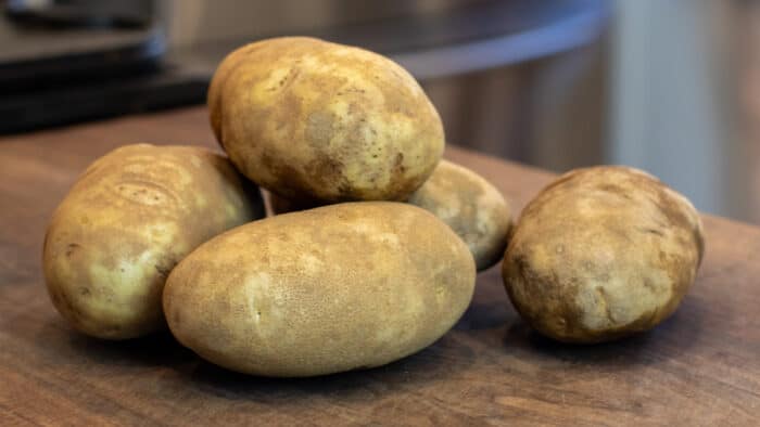 Russet potatoes stacked on a cutting board