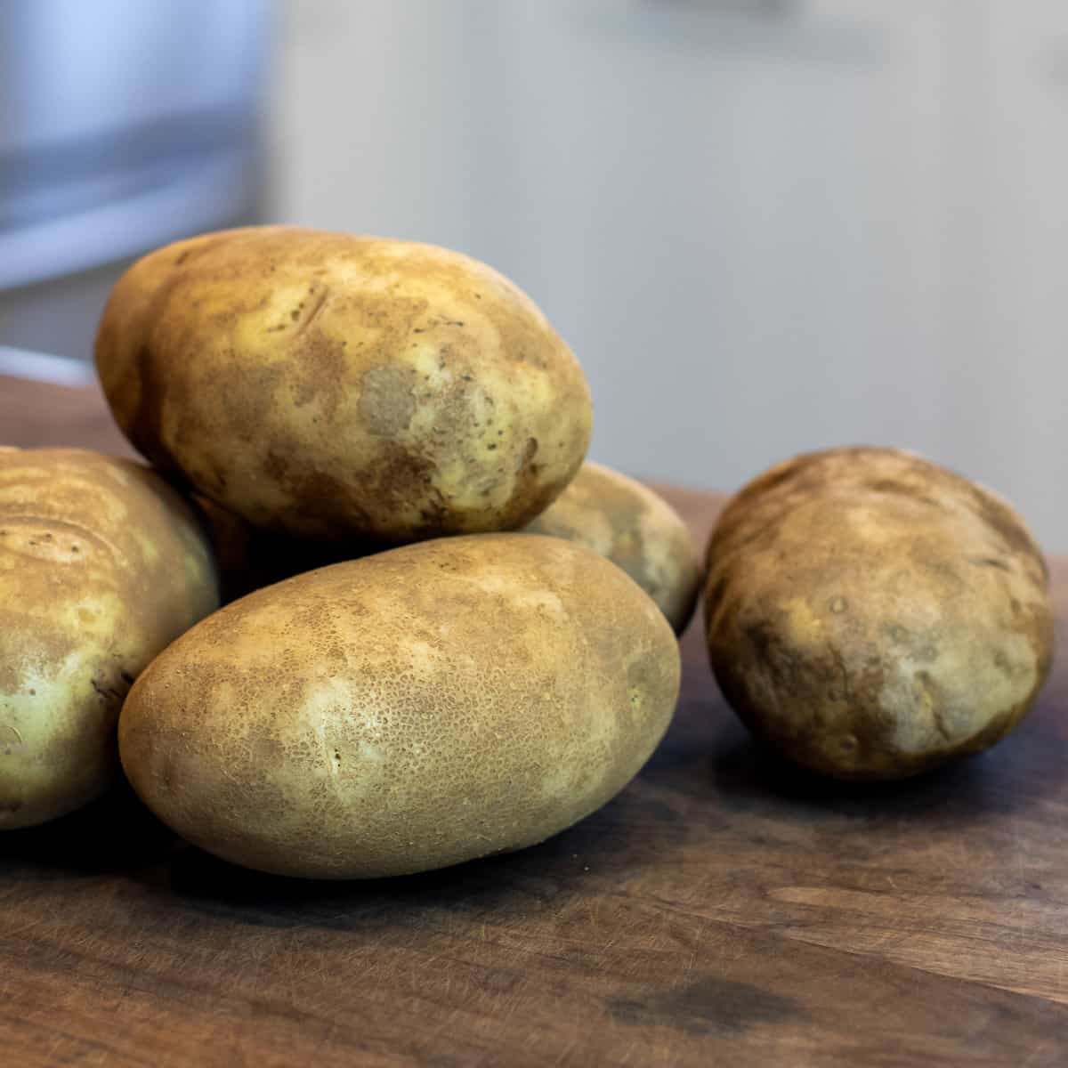 Raw whole potatoes on a cutting board.