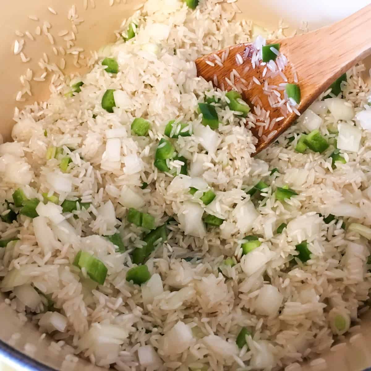 Diced onion, jalapeno and raw rice in a dutch oven.