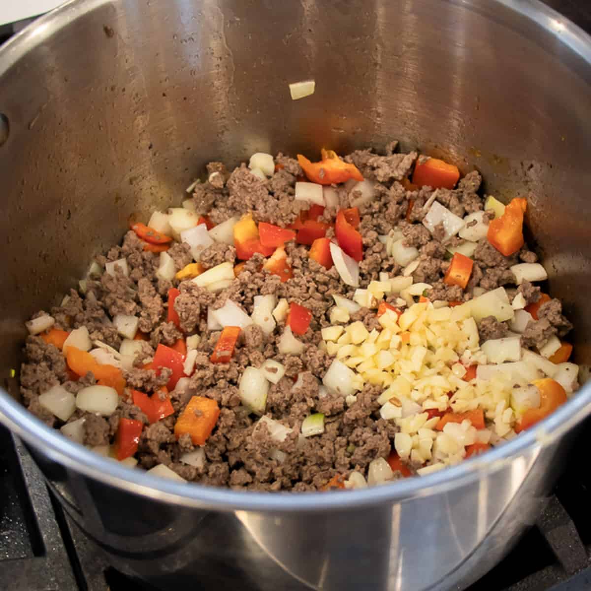 A large pot with cooked ground beef, onions and red pepper.