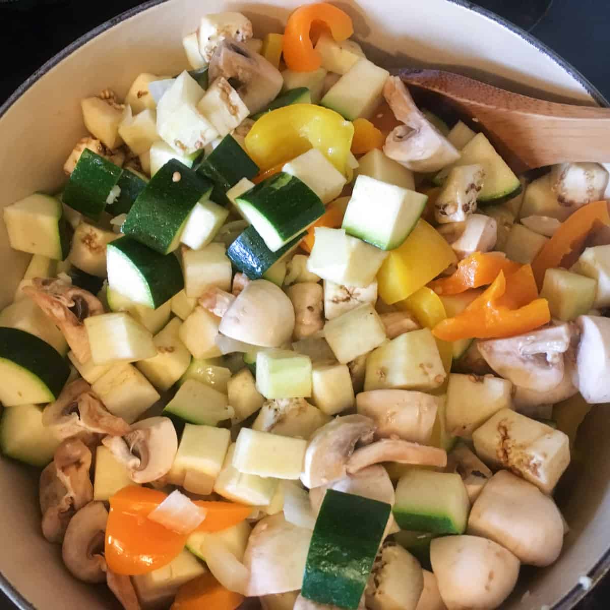 Chopped zucchini and other vegetables in a dutch oven.