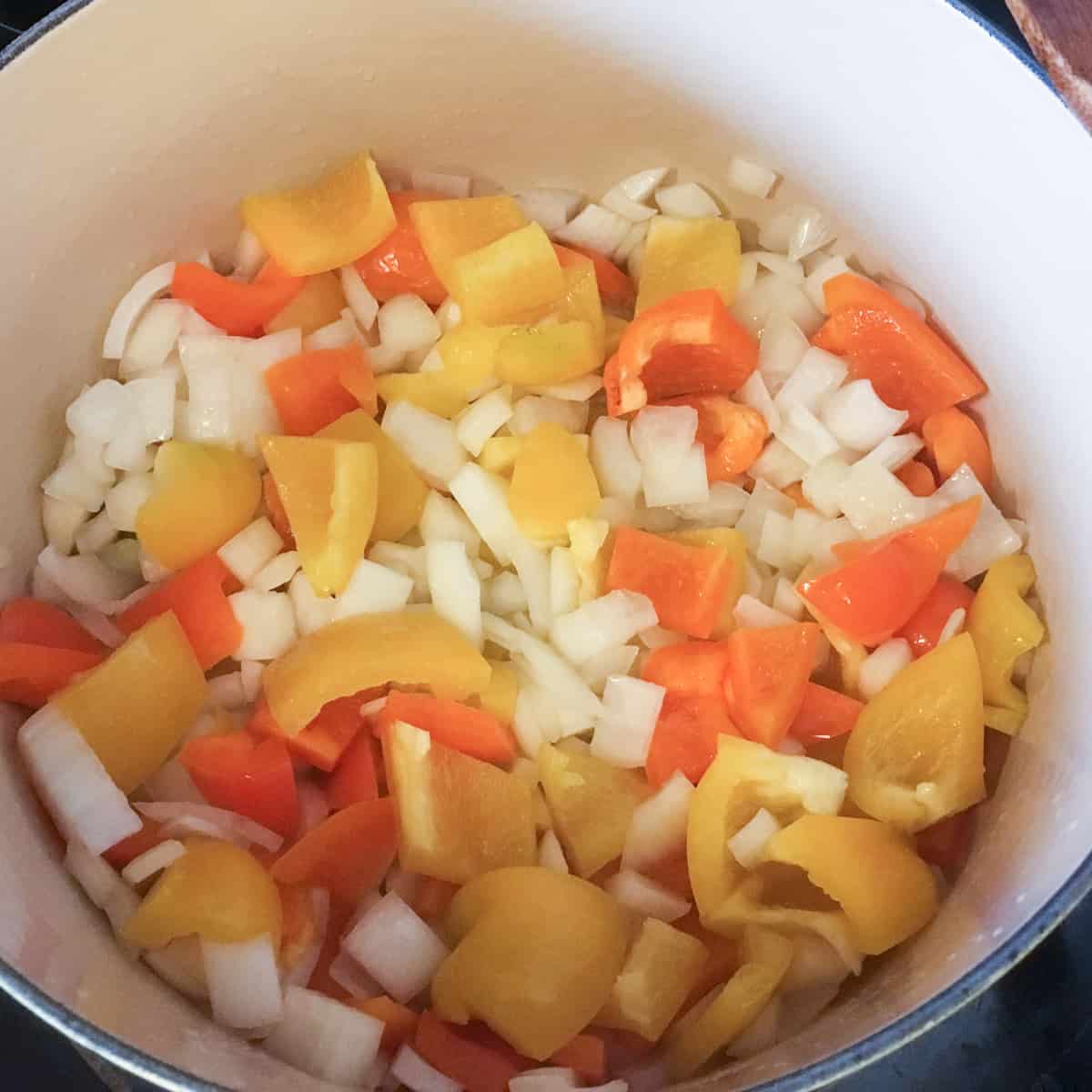 Onions and peppers sautéing in a dutch oven.