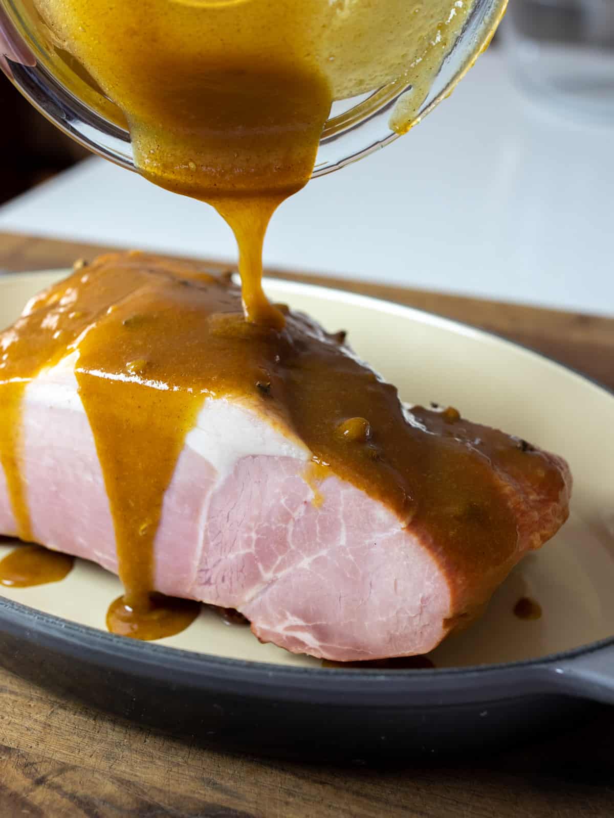 Ham with glaze being poured all over it.