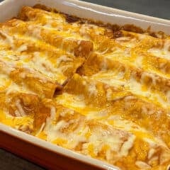 Ten baked enchiladas in a rectangular dish.
