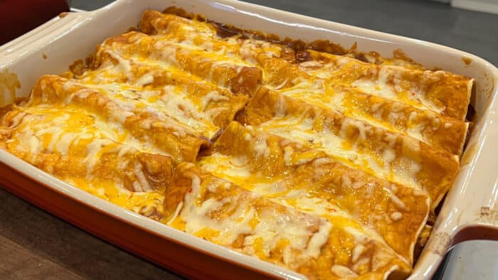 Ten baked enchiladas in a rectangular dish.